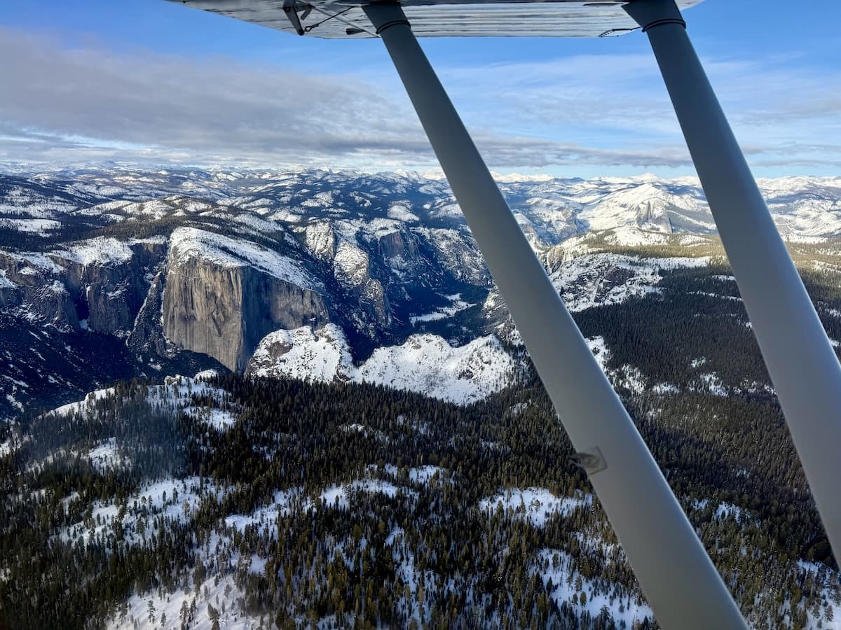 Aerial cockpit view of snow-covered Yosemite Valley mountains during a general aviation flight tour.