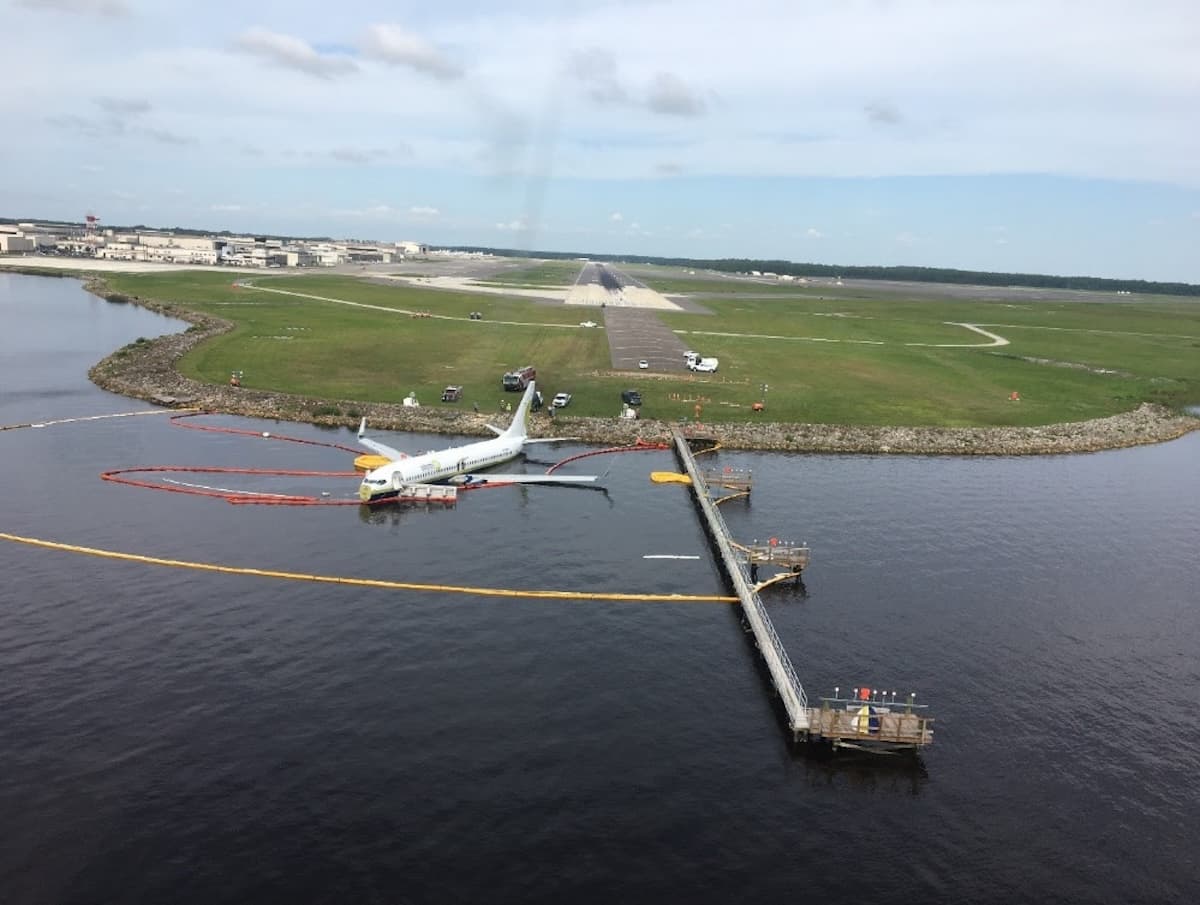 Boeing 737 resting in the shallow water of St. Johns River after a runway overrun during heavy rain.