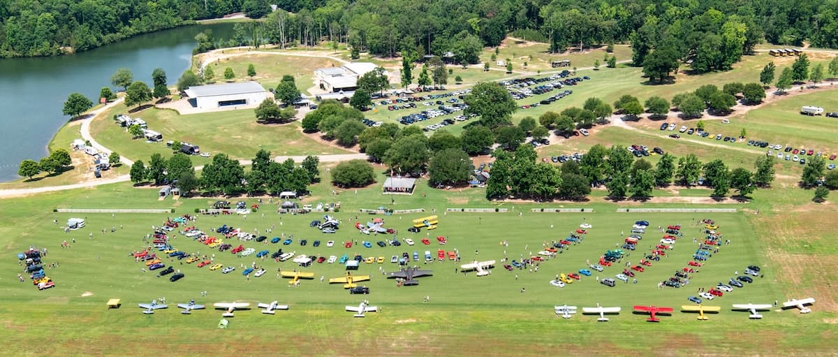 Aerial view of classic cars and vintage aircraft on the turf at Triple Tree Aerodrome during the Pistons and Props event.