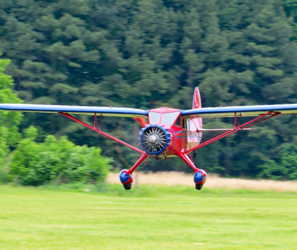 1935 Stinson SR-6B vintage antique airplane landing on the grass runway at Bradford Field.